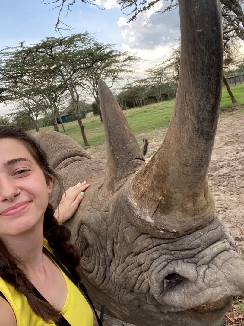 Rita with her hand on rhino's head in Kenya
