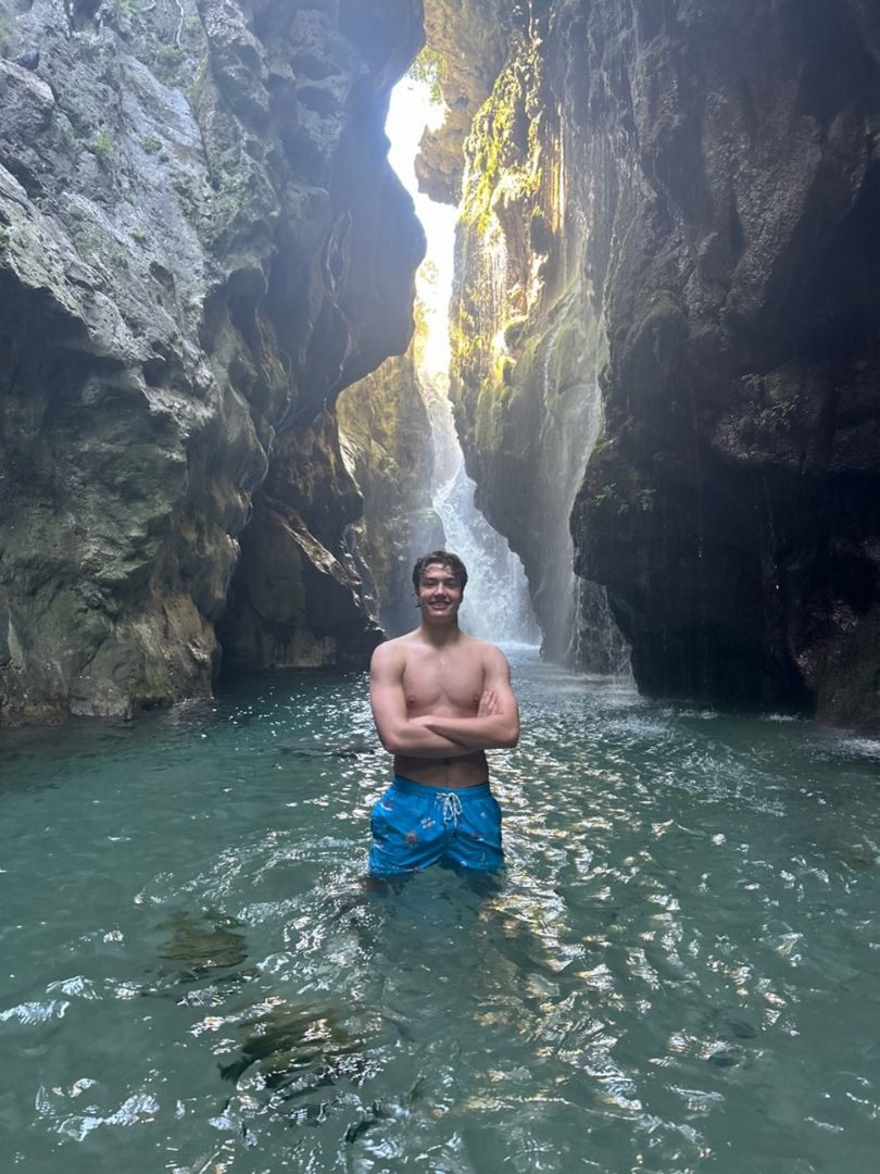 Nicholas standing in a swimming suit in a sea cavern in Greece