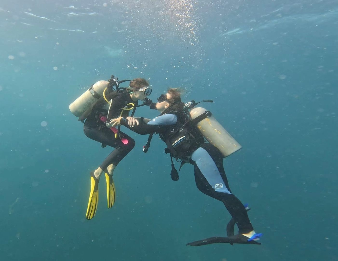 Lyric and friend embracing underwater in their scuba gear