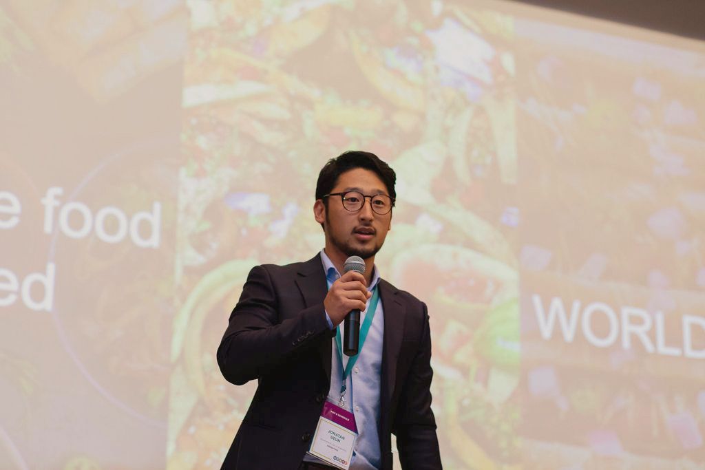 Jonatan Beun, standing on stage at the Global Youth Advancement Summit during his presentation of Food For All
