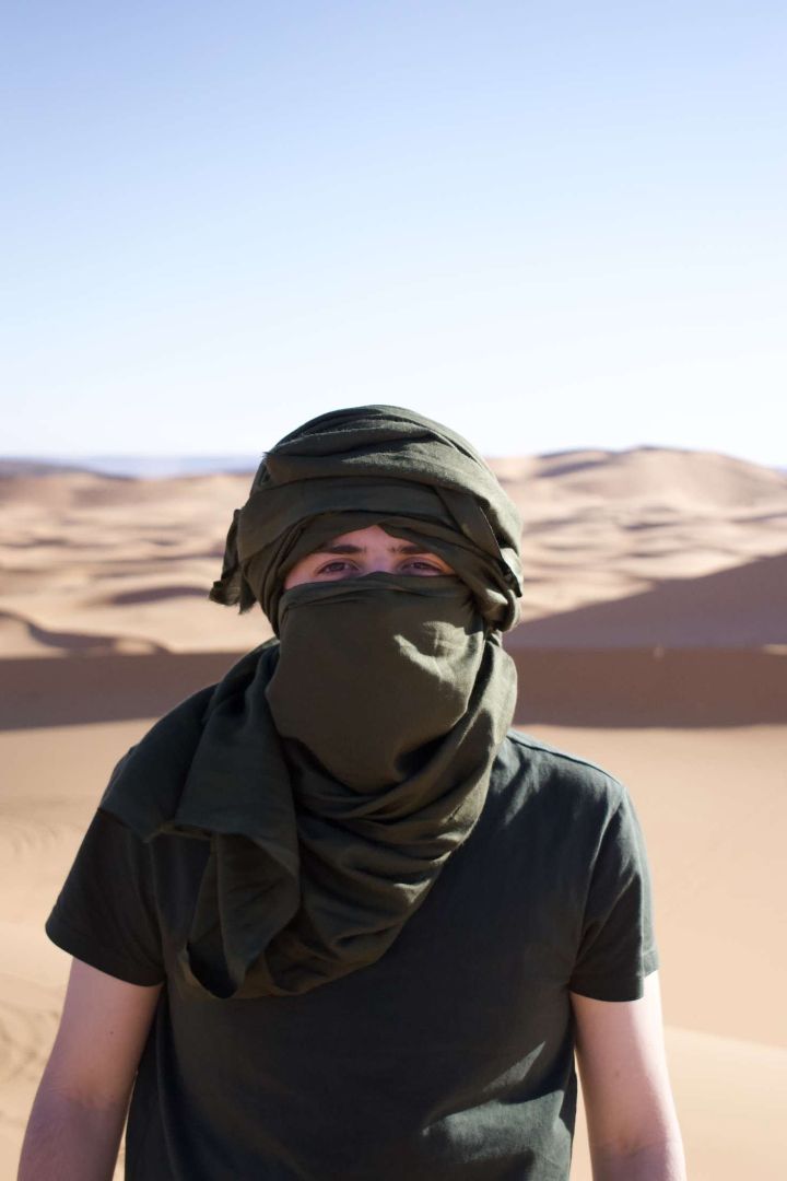 Kyle wearing a traditional headscarf in a desert