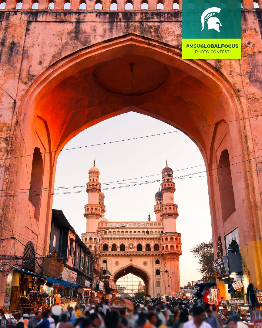 A stone archway in Charminar, Hyderabad, India with a crowd of people walking under it