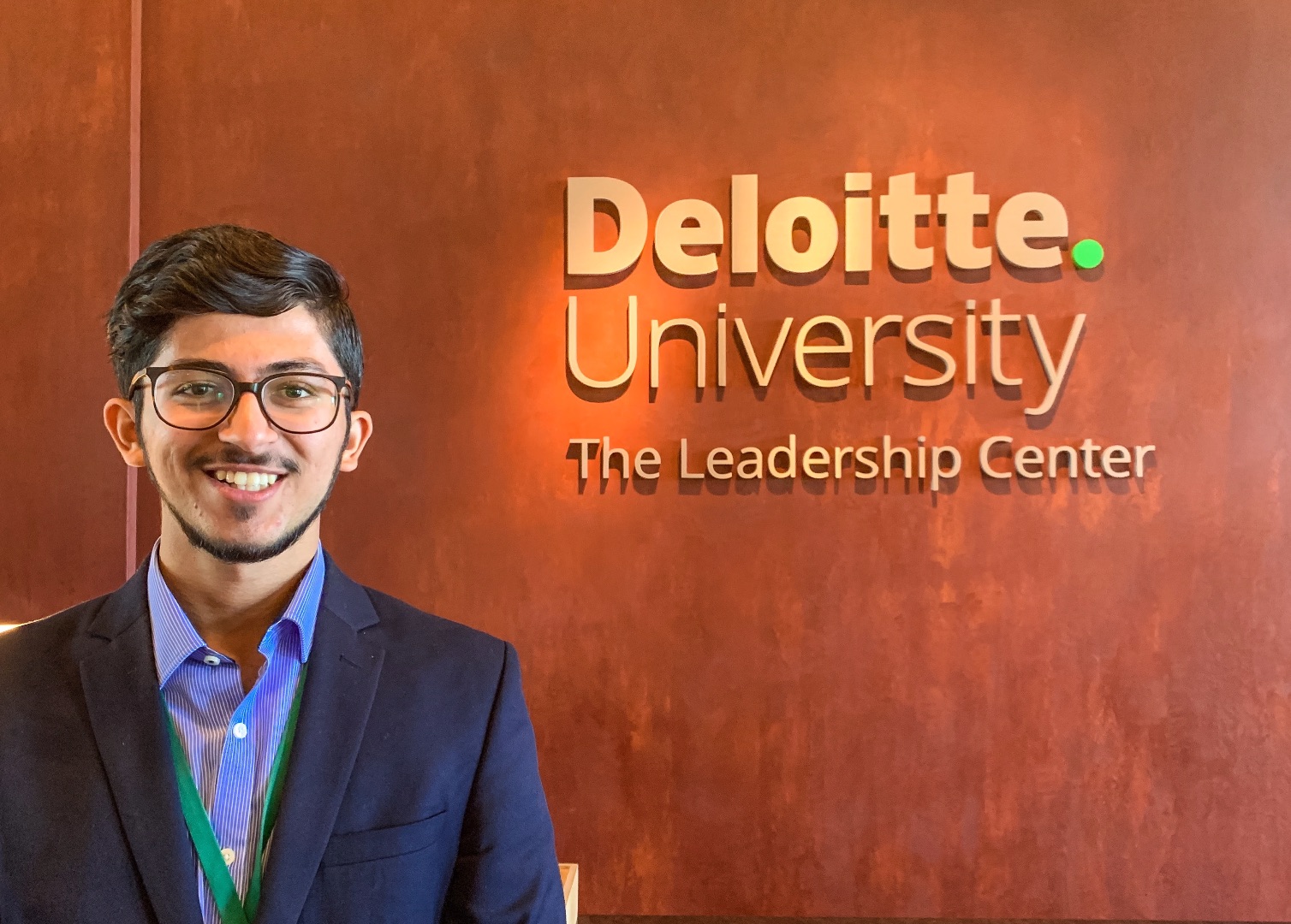 Man posing next to sign that says Deloitte University The Leadership Center