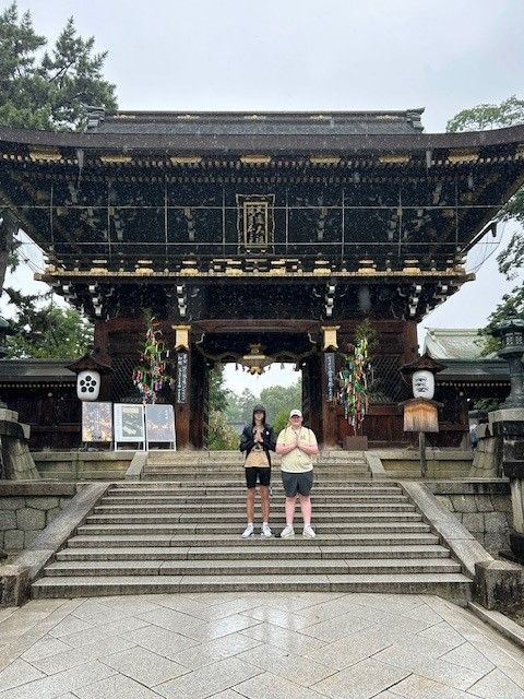 Xander and friend staning on the steps of a shrine in the rain in Japan