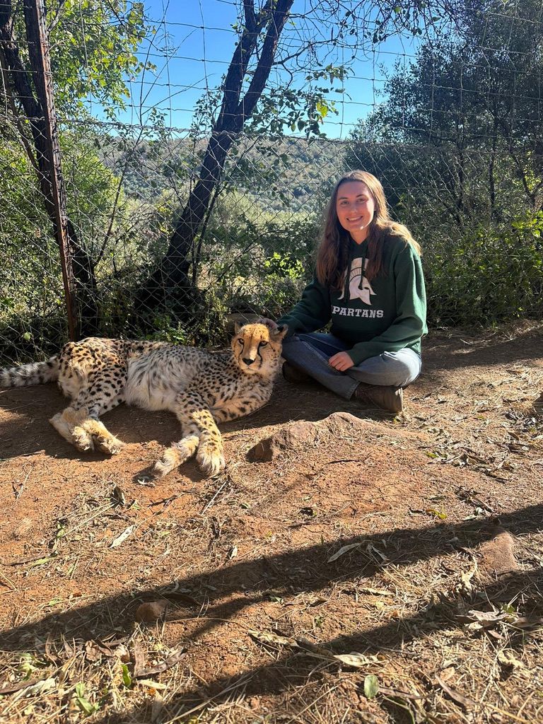Makenna wearing a Spartan hoodie sitting next to a cheetah