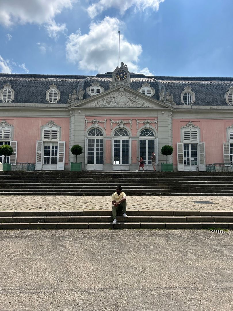 Clifton sitting on steps outside of a pink-colored palace in Europe