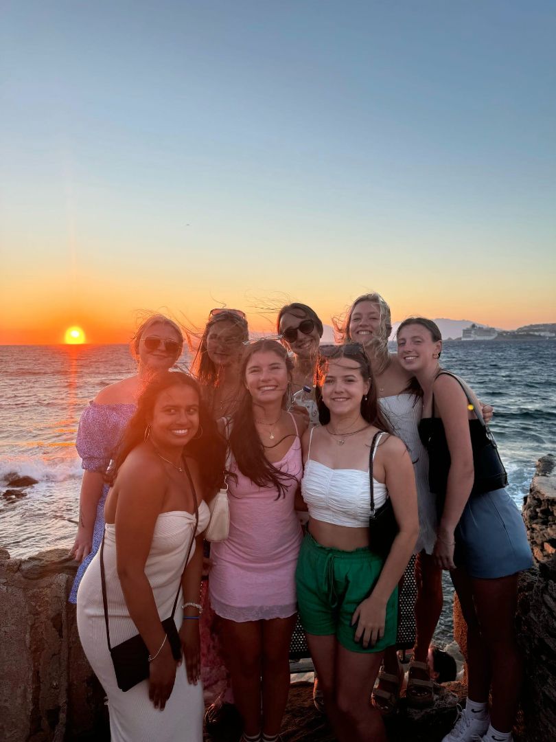 Anne with a group of friends posing at sunset near the sea in Greece