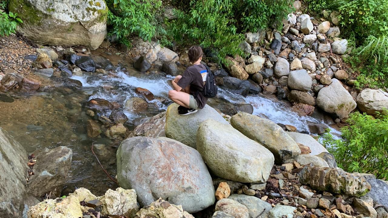 Hazel sitting on large boulder along a stream in Costa Rica