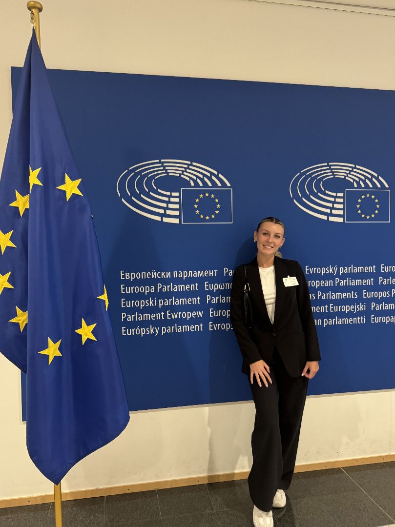 Yuliya standing next to the flag of the European Union