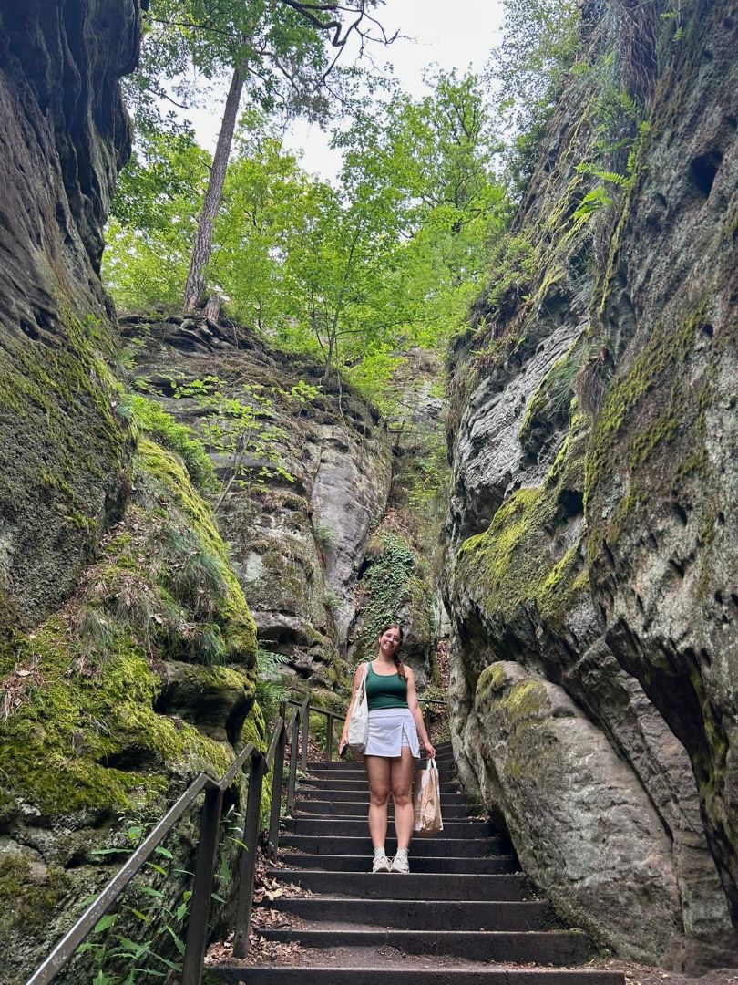 Alex standing on stone stairs in a forest in Germany