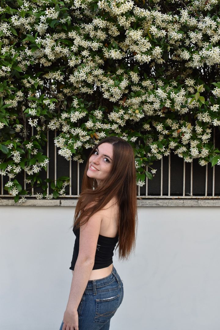 Julia posing in front of some bushes with white flowers in Italy