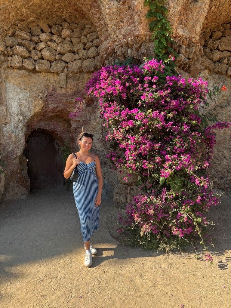 Nicole poses in a white and navy striped dress next to a tree full of pink flowers