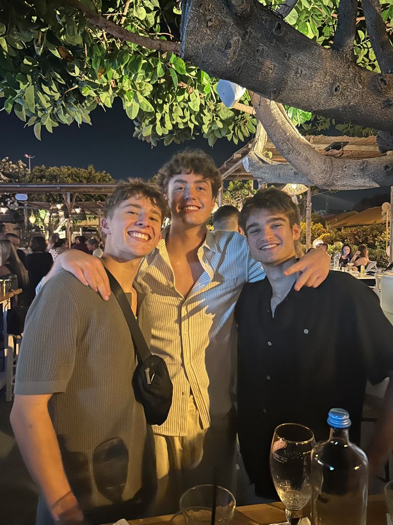 Brady standing under a tree at night with two friends in Greece