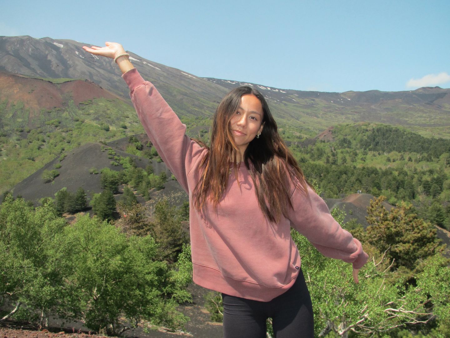 Jade posing on a mountain with her right arm raised