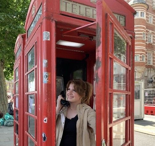 Victoria pretending to talk on telephone in iconic red London phonebooth