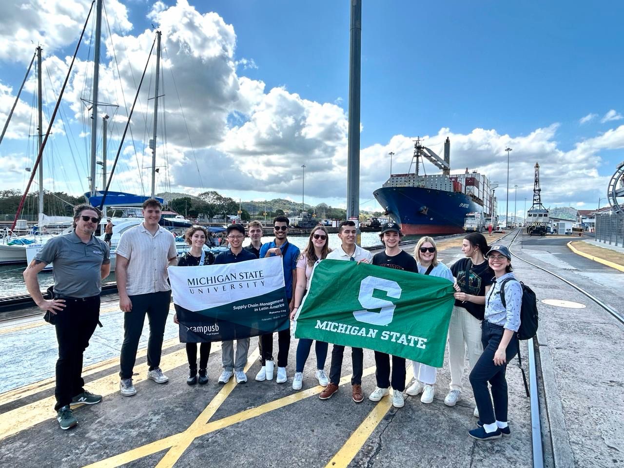 MSU students holding Spartan flags on the docks of the Panama Canal