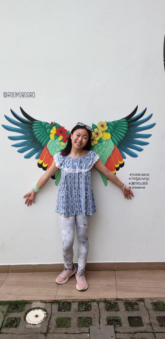 Waincey standing in front of wall painted with butterfly wings in Costa Rica