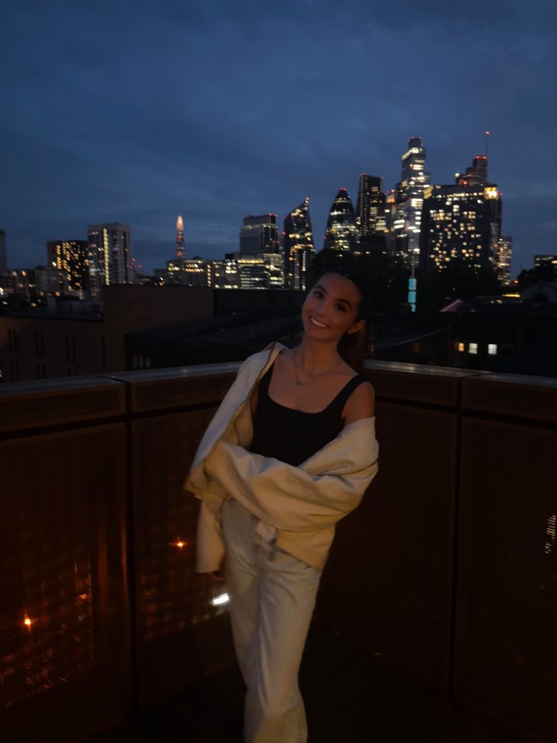 Isabella standing on a balcony at night in London