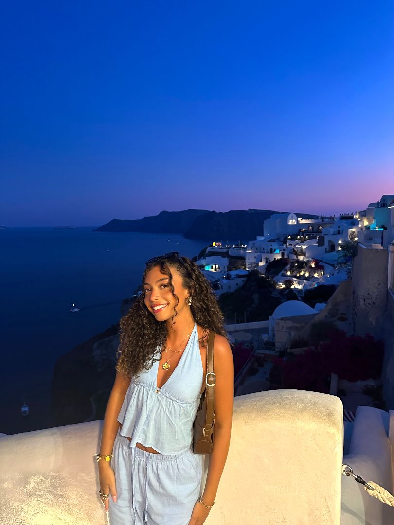 Adreana standing on a stone balcony overlooking the sea at night