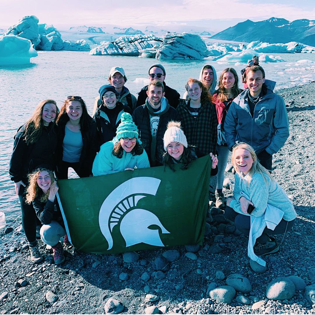 Students holding Spartan flag on glacier in Iceland