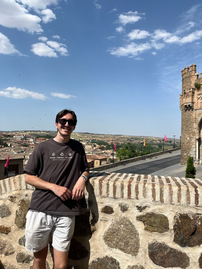 Evan leaning on a stone wall on top of a building in Spain