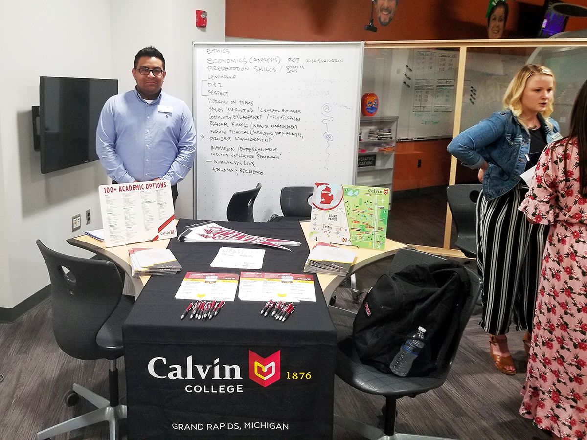 Representative from Calvin College at MSU {male standing in front of a table with Calvin College information on table}