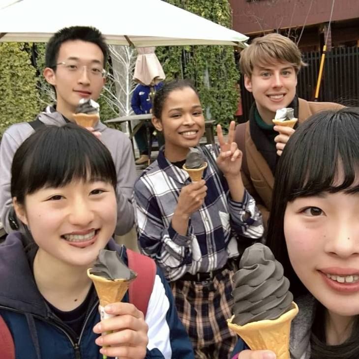 5 smiling people holding black ice cream 
