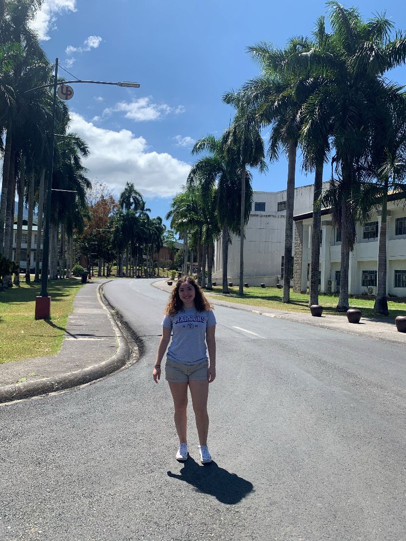 Jacqueline Rodriguez standing by palm trees on UPLB campus in the Philippines
