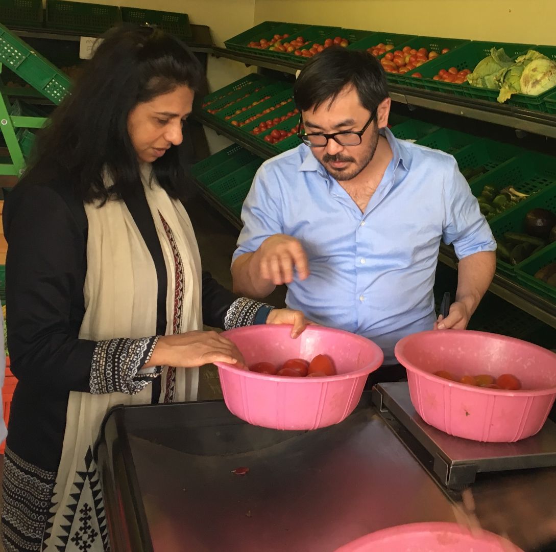 Mywish Maredia with a male colleague, inspecting a bowl of vegetables