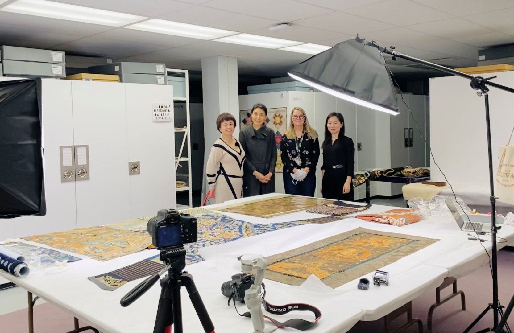 Chenxue Huang, Dr. Xia Gao, Lynne Swanson, and Luna Lu standing behind tapestries