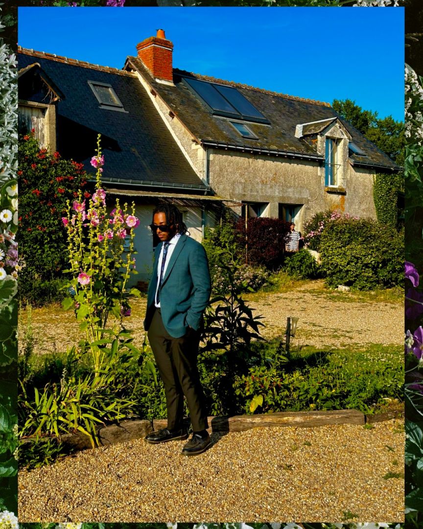 Joe standing in a French garden wearing a green blazer and sunglasses