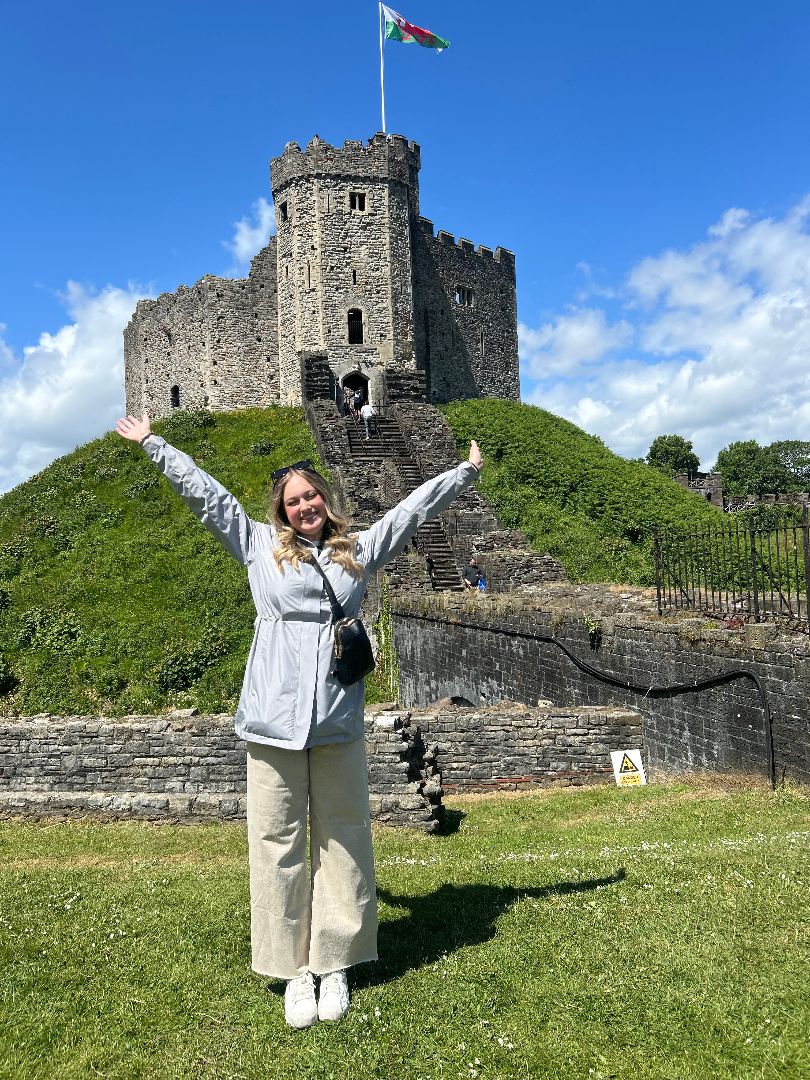 Caroline with her hands held high in front of a castle