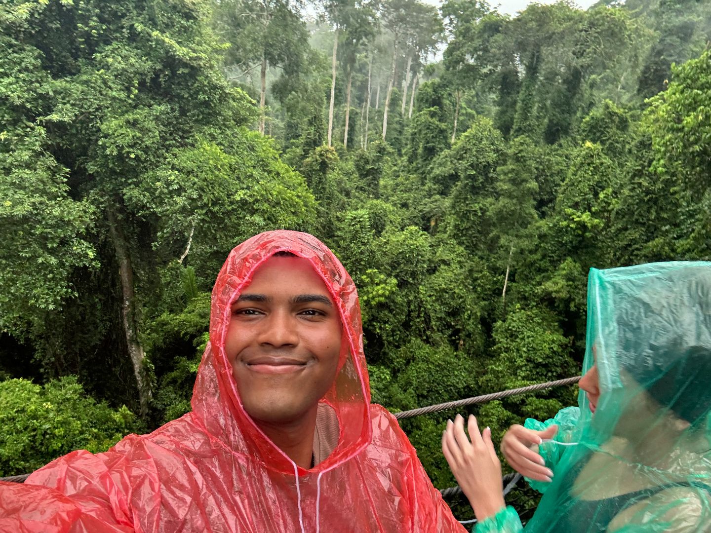 Latrell wearing a red rain poncho in the rainforest
