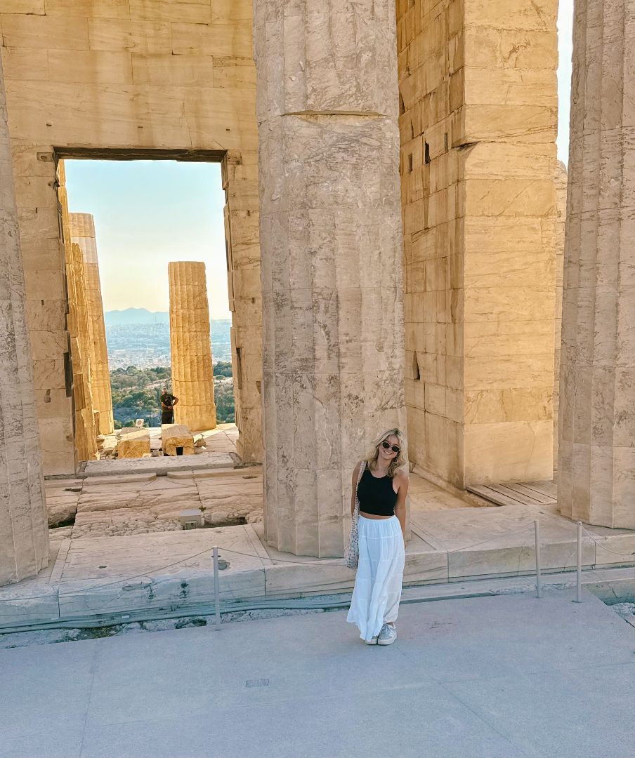 Anna standing next to a large column of the Acropolis
