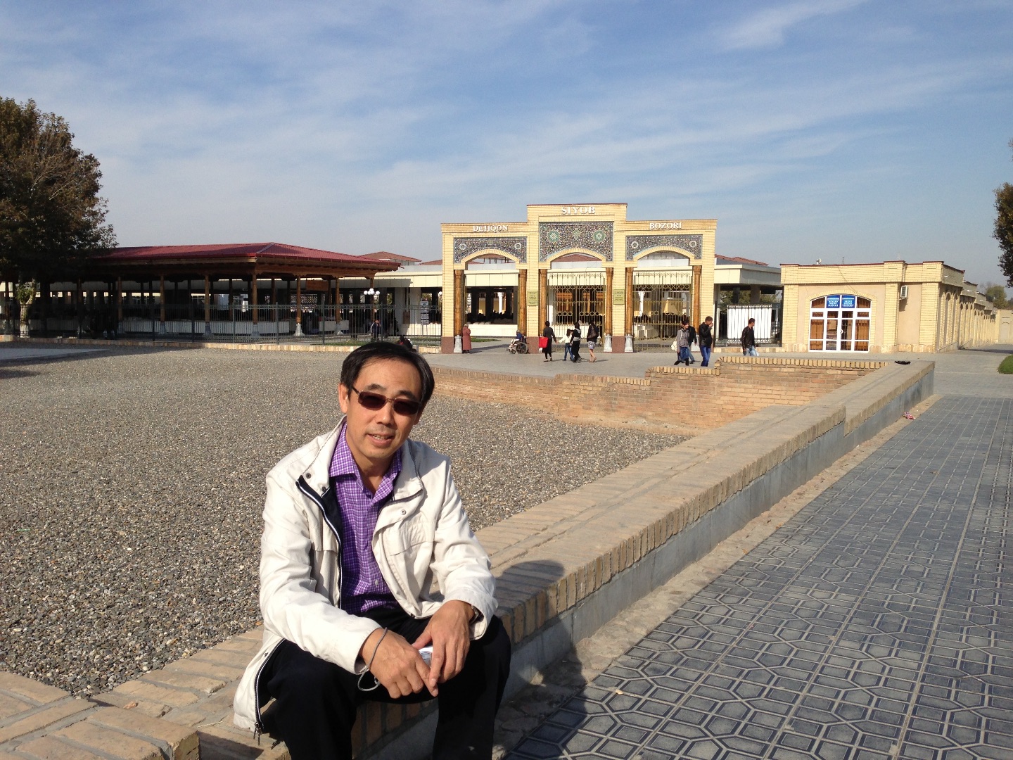 Dr. Qi sits on the curb holding a knee in front of a building in Asia