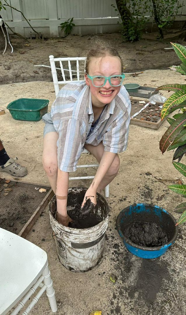 Deanna in Belize with her hands in a bucket of mud