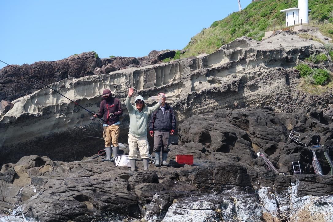 A photo of local fishermen standing on a cliff in Japan