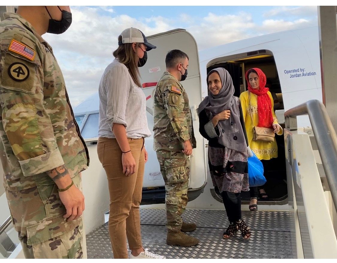 Two GRAIN scholars deboard a plan and are greeted by masked military personnel and a congresswoman