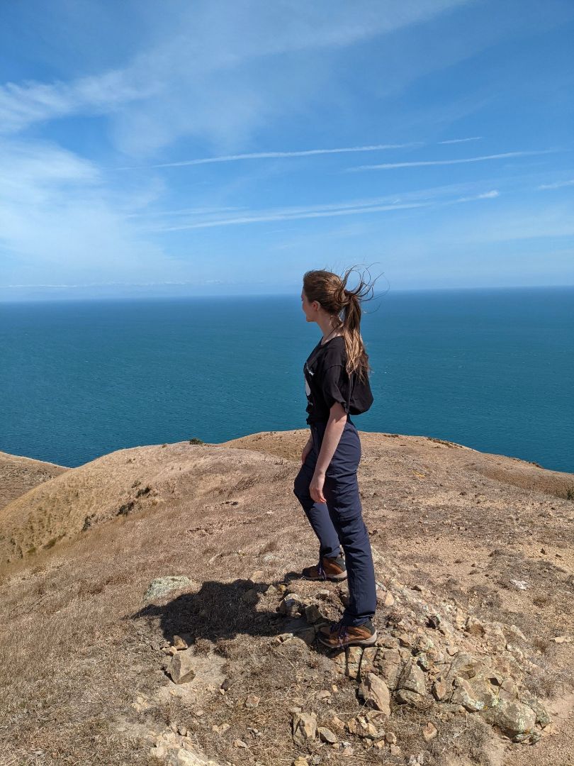 Rebecca standing on top of a cliff overlooking the ocean in New Zealand