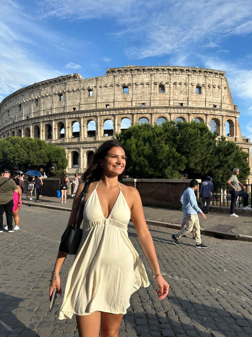 Lauren wearing a white dress standing in front of the Roman Colesium