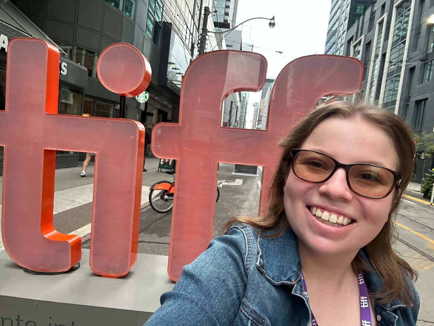 Ariel takinga selfie in front of a large, red TIFF sign