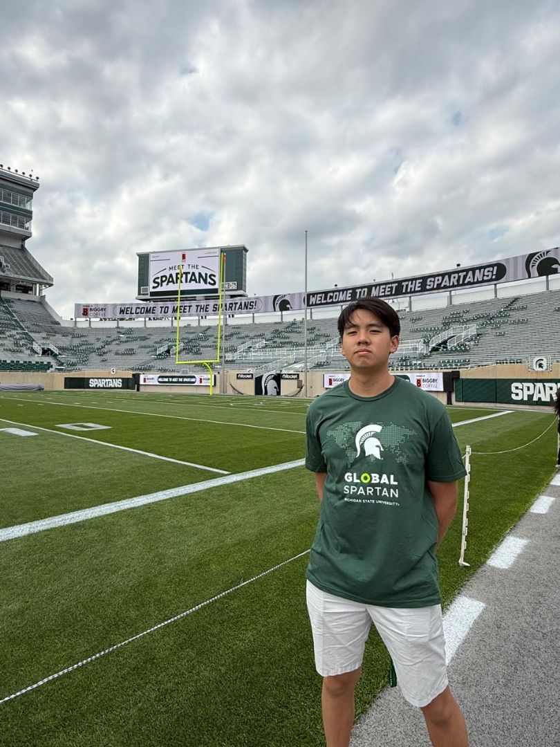 Logan standing in front of the MSU football field