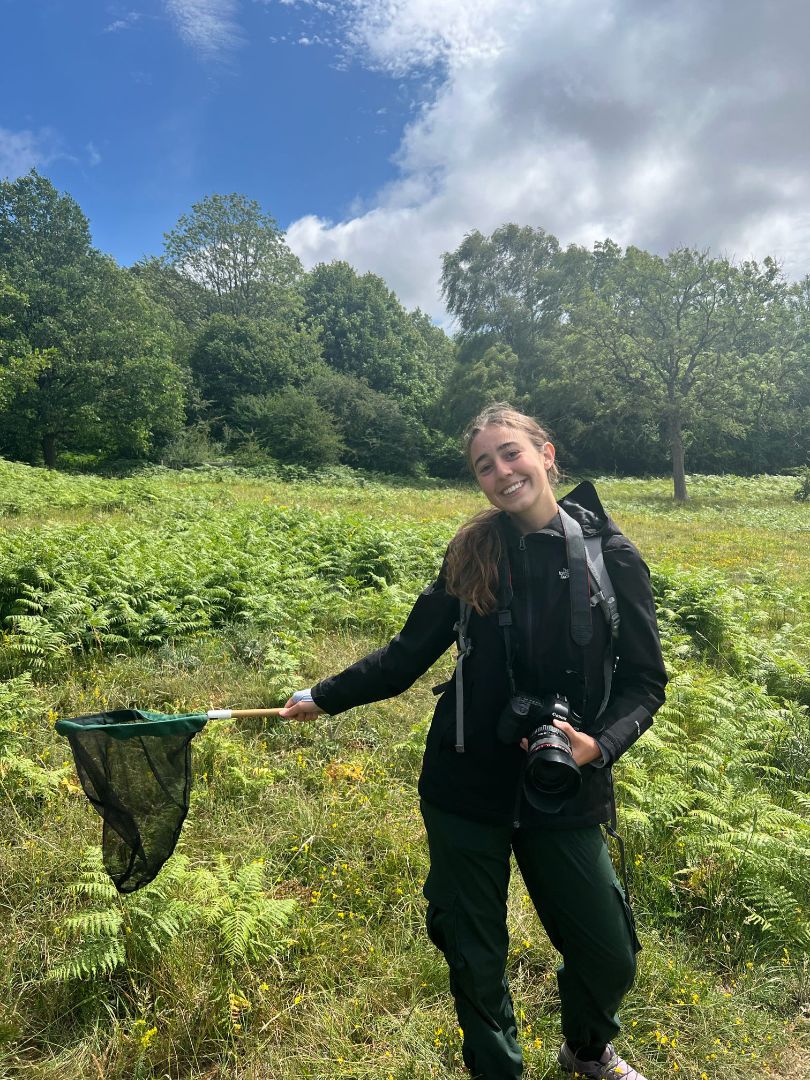 Grace holding a net and camera doing fieldwork