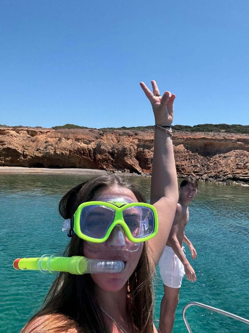 Madison wearing snorkeling gear raising the peace sign  while on a boat in Greece