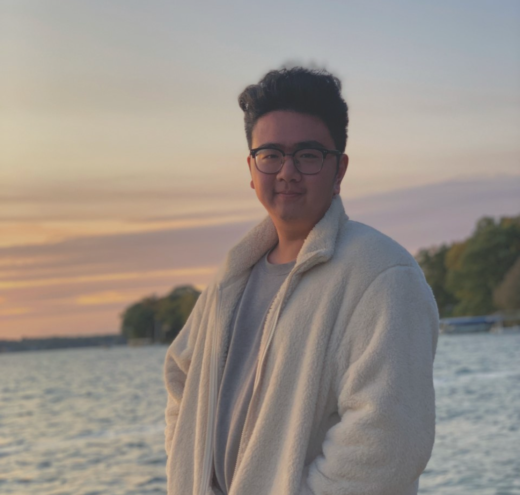 Shawn stands in front of Lake Michigan with the sun setting