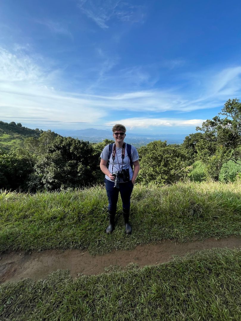 Finley holding pair of binoculars and standing on top of mountain in Costa Rica