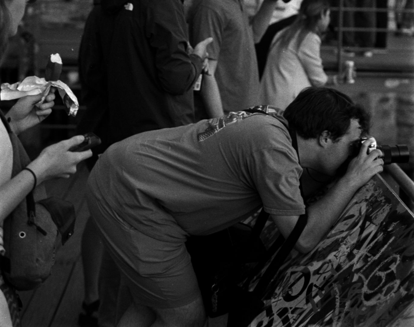 Black and white photo of a student taking a photo through a bridge