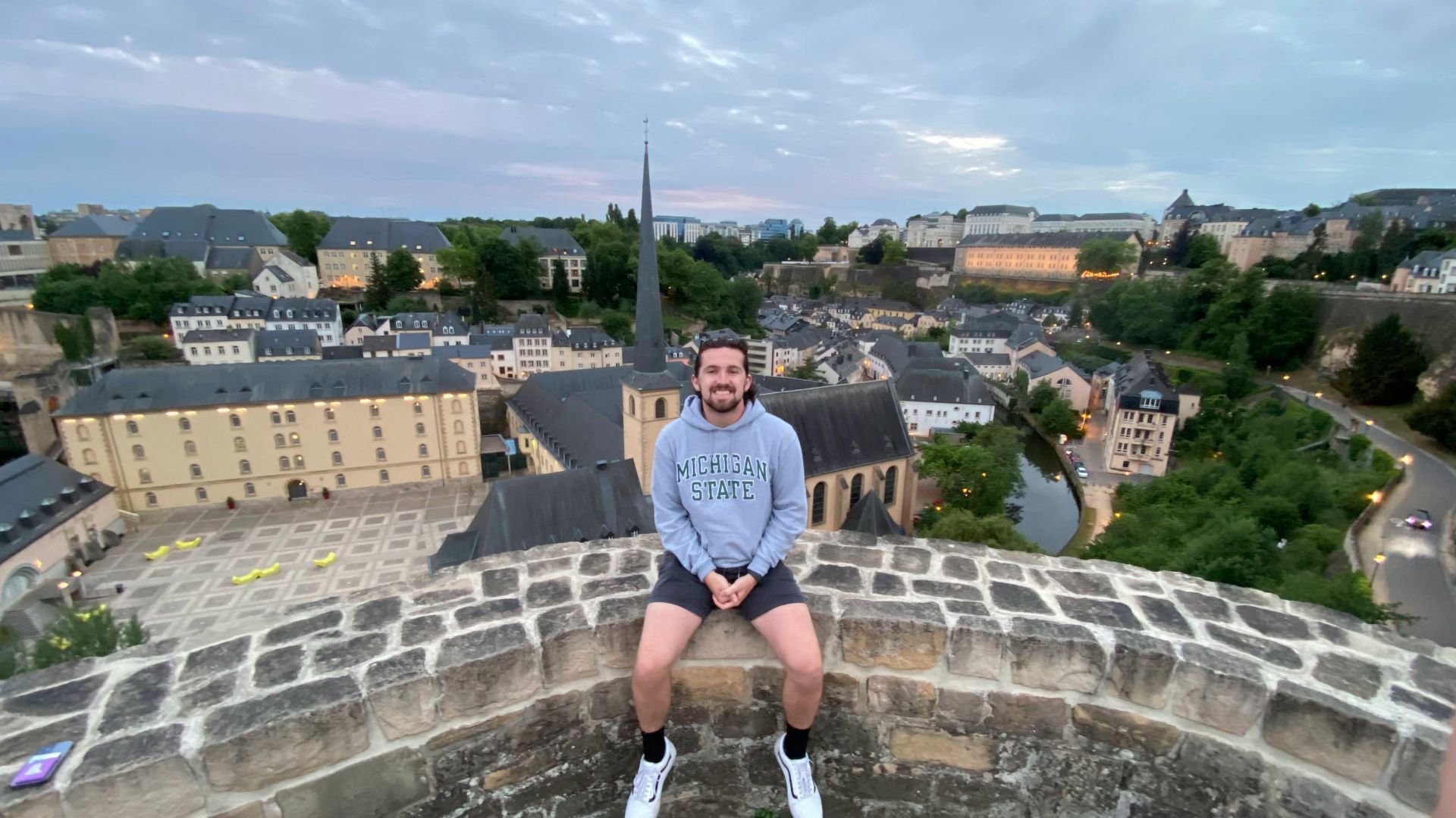 Garret sitting on stone wall overlooking Luxembourg