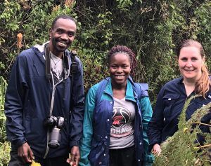 Sarah Corner stands with two Ugandan veterinarians in front of a lush green background.