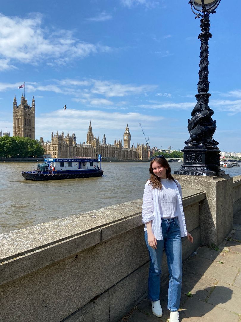 Ellie standing along the Thames in London with Parliament in the background